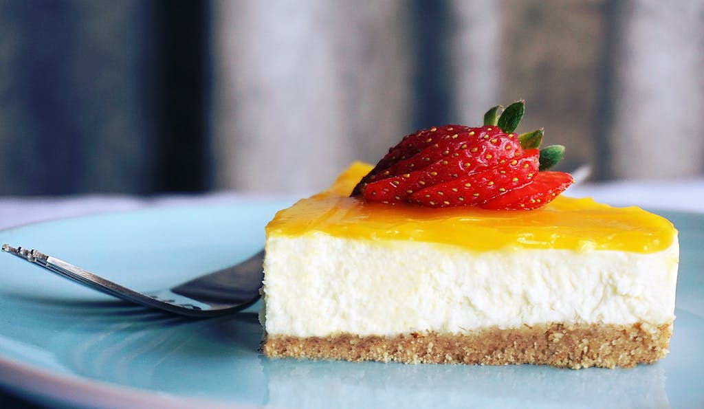 Close-up of a creamy cheesecake slice topped with vibrant strawberries, perfect dessert treat.